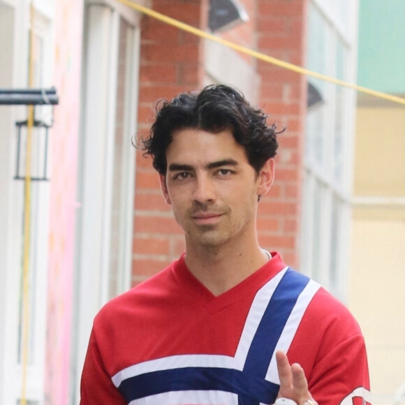 Joe Jonas fait le signe de paix et tout en rouge vêtu d'un maillot norvégien lors de ses déplacements dans le quartier de West Village à Manhattan.