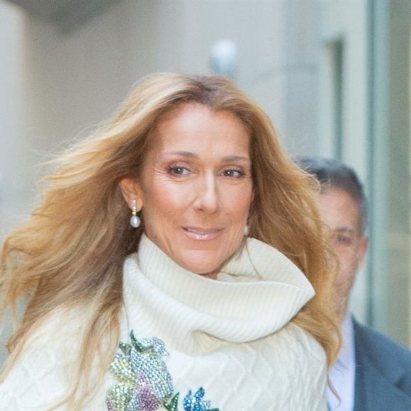 Celine Dion rayonnante et très souriante dans un ensemble pull écru et jupe bouffante fleurie salue ses fans à la sortie de son hôtel à New York, le 8 mars 2020 
