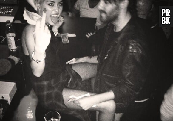 Miley Cyrus pose jambes écartées avec un doigt d'honneur