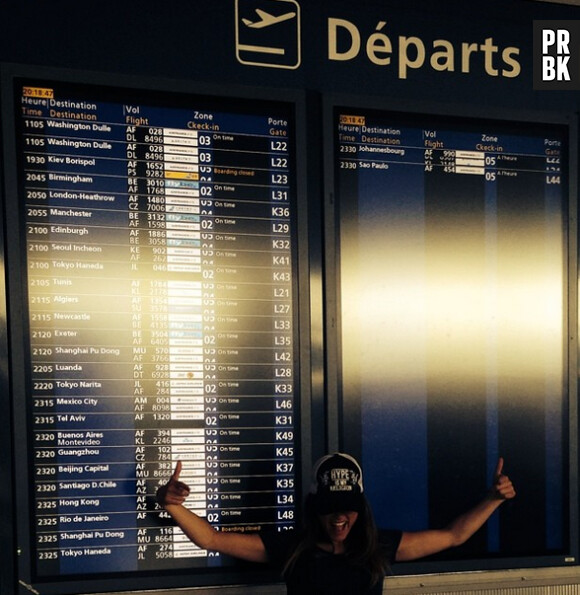 Capucine Anav : devant le panneau des départs, à l'aéroport, pour son vol pour Hong Kong