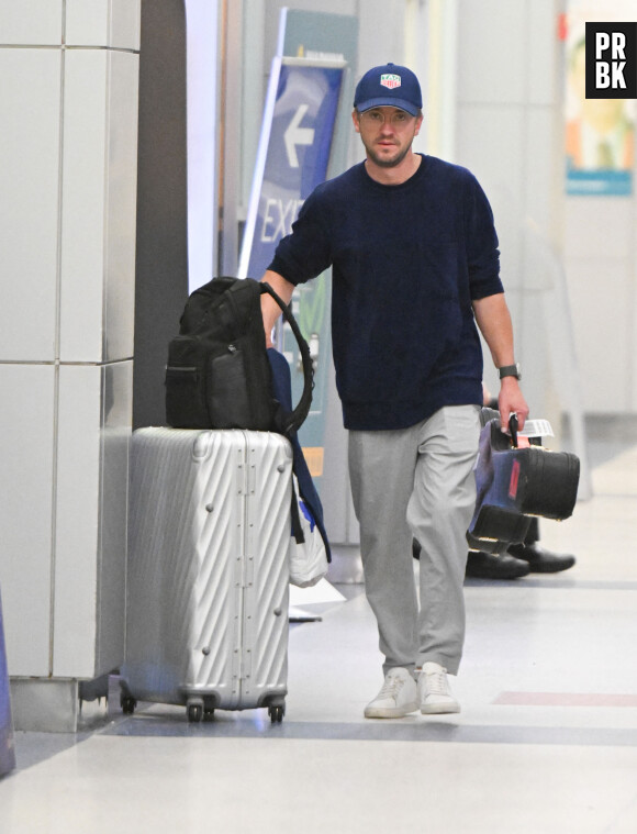 Exclusif - Tom Felton porte sa guitare en arrivant à l'aéroport JFK de New York City, New Yor, Etats-Unis, le 17 octobre 2022.  Exclusive - Harry Potter star Tom Felton seen carrying his guitar while walking with a woman thru JFK airport in New York City. The sighting comes after Felton revealed in a new memoir that he 'always had a secret love' for co-star Emma Watson. 