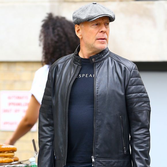 Bruce Willis se promène sur Prince Street à Soho, il porte une casquette grise et un parapluie rouge, New York, le 21 juin 2019.