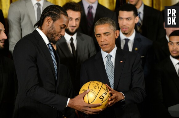 Barack Obama reçoit un ballon de basket signé par les joueurs des San Antonio Spurs, le 12 janvier 2015 à la Maison Blanche (Etats-Unis)