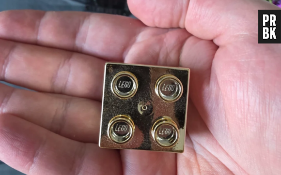 Un employé de LEGO montre ce qu'il a reçu pour son quatrième anniversaire : une brique Lego dorée que nous voulons tous avoir maintenant